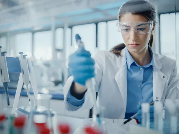 Científica en laboratorio usando micropipeta para análisis biomédico.