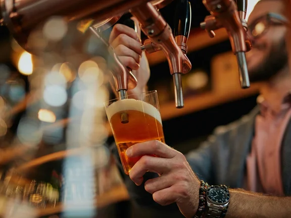 Hombre sirviendo cerveza en un vaso de vidrio.