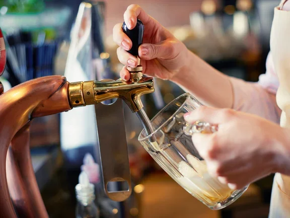 Manos sirviendo cerveza directamente en un vaso de vidrio.