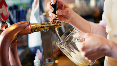 Manos sirviendo cerveza directamente en un vaso de vidrio.